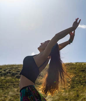 A woman with long hair and a black shirt is stretching her arms up. Beschreibung von KI generiert