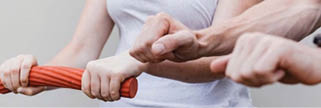 Several people are gripping and pulling on a thick red rope in a coordinated effort. Beschreibung von KI generiert