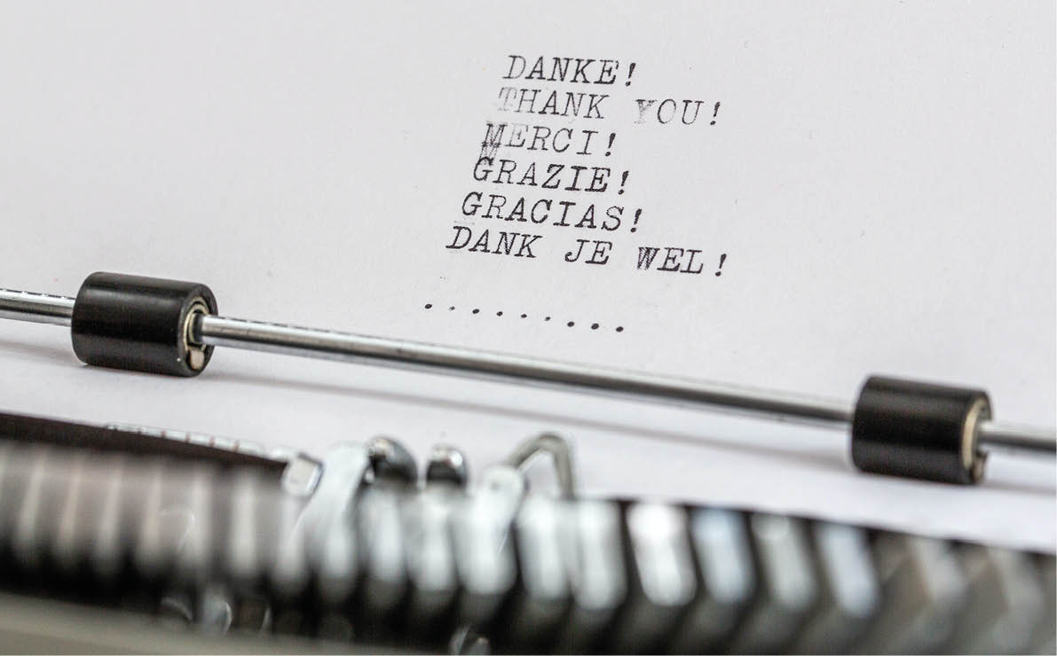A typewriter with a sheet of paper displaying the words thank you in multiple languages including German, English, French, Italian, Spanish, and Dutch. Beschreibung von KI generiert