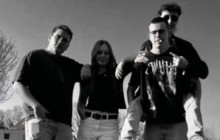 Four people stand close together outdoors against a clear sky, with two wearing glasses and one making a hand gesture. Beschreibung von KI generiert