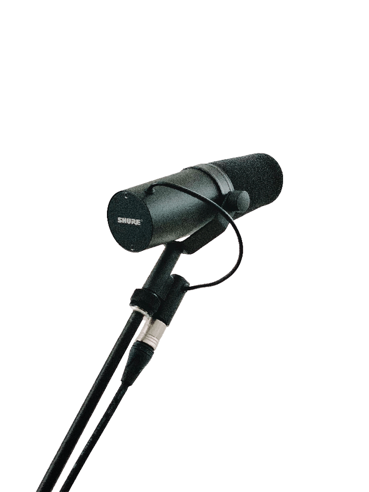 A black Shure microphone is mounted on a stand with a cable connected to it against a plain light background. Beschreibung von KI generiert