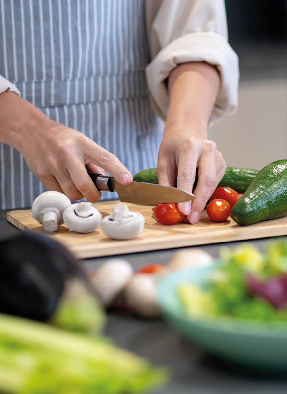 Cutting veggies. Woman cooking lunch and cutting vegetables