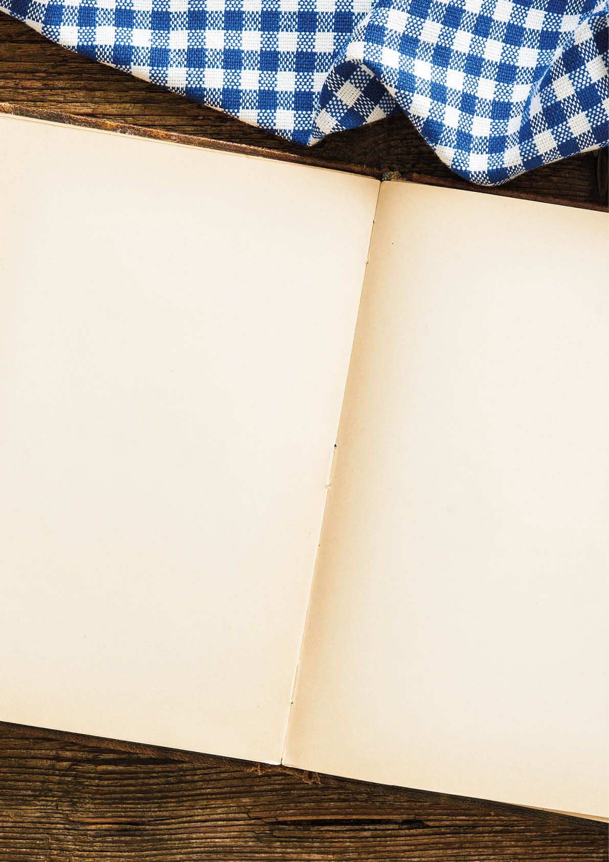 Open cookbook with kitchenware on checkered tablecloth